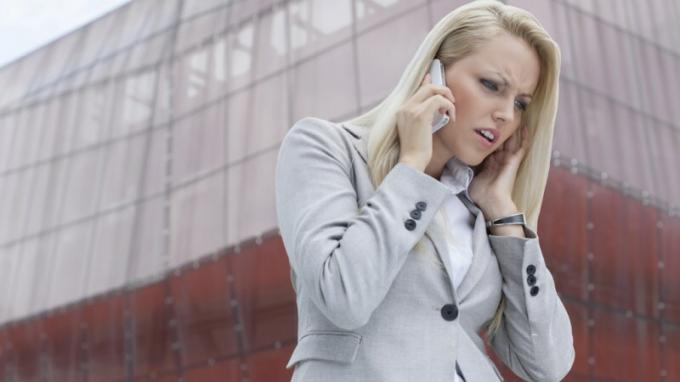 एडीएचडी वाली महिला सेल फोन पर किसी की सुनती है और ऊंची इमारत के सामने गुस्सा करती है